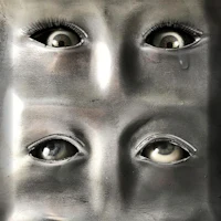 a metal sculpture with three eyes on it
